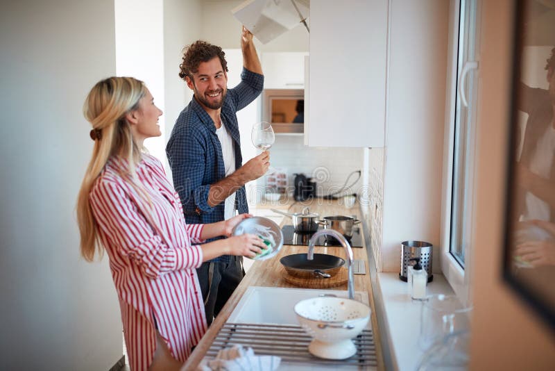 A young couple washing dishes together. Kitchen, housework, home, relationship