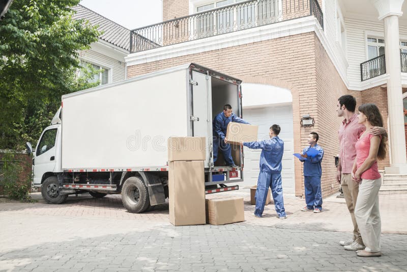 Giovane coppia guardando movers spostare le caselle dal furgone in movimento.