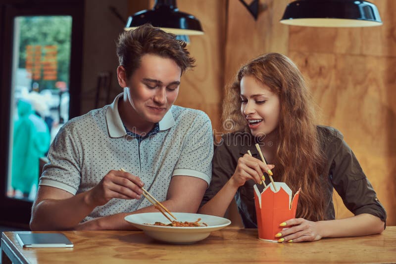 Young couple wearing casual clothes eating spicy noodles in an Asian restaurant.