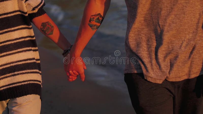 Young couple woman and man on sandy beach at sunset. hands close up