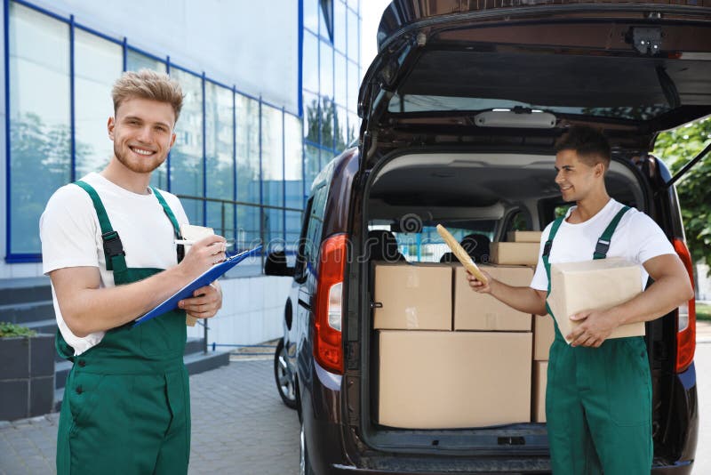 Young couriers with parcels near delivery car stock photography