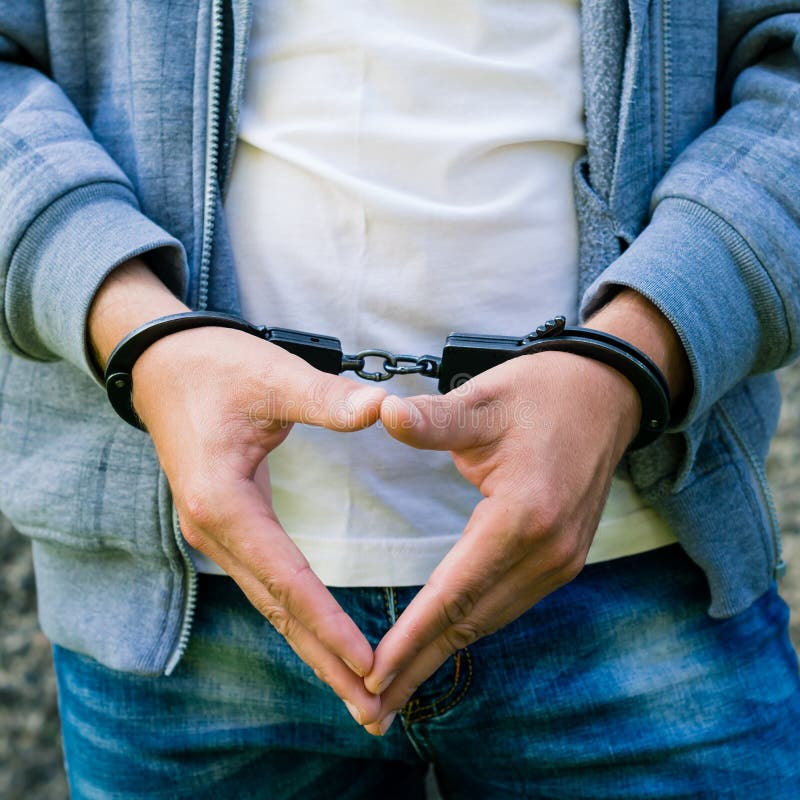 Young criminal standing in handcuffs, outdoors. Concept of crime stock photos Young criminal standing in handcuffs, outdoors. Concept of crime stock photos