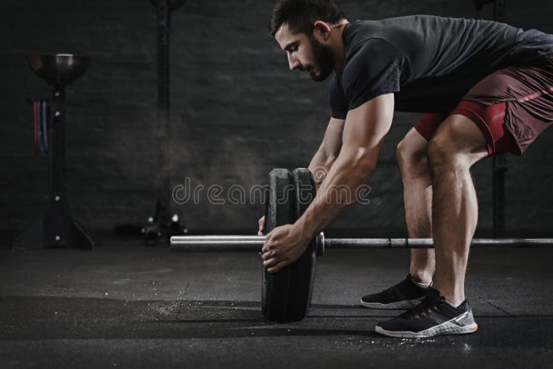 Young crossfit athlete preparing barbell lifting weight at the gym. Magnesia protection dust cloud. Handsome man doing functio royalty free stock photography Young crossfit athlete preparing barbell lifting weight at the gym. Magnesia protection dust cloud. Handsome man doing functio royalty free stock photography