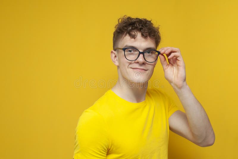 Young Curly Smart Guy Holding Glasses on Yellow Background and Smiling Stock Image Image of