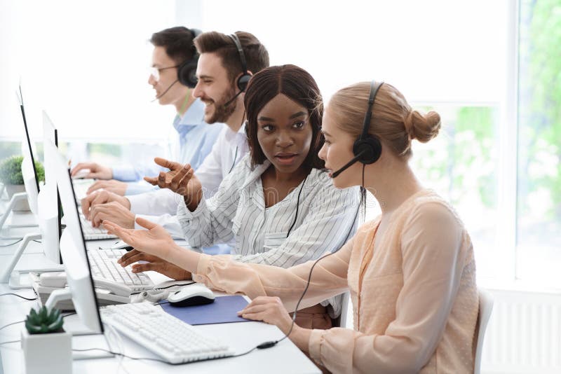 Young customer support workers solving clients problem together at call centre office