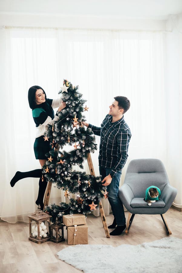 Young Cute Couple Decorate a Christmas Tree on Christmas Eve Stock