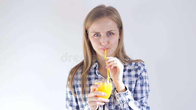 Young girl drinks orange juice through a straw
