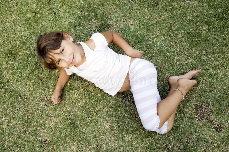 Young cute girl lying on the grass stock photo