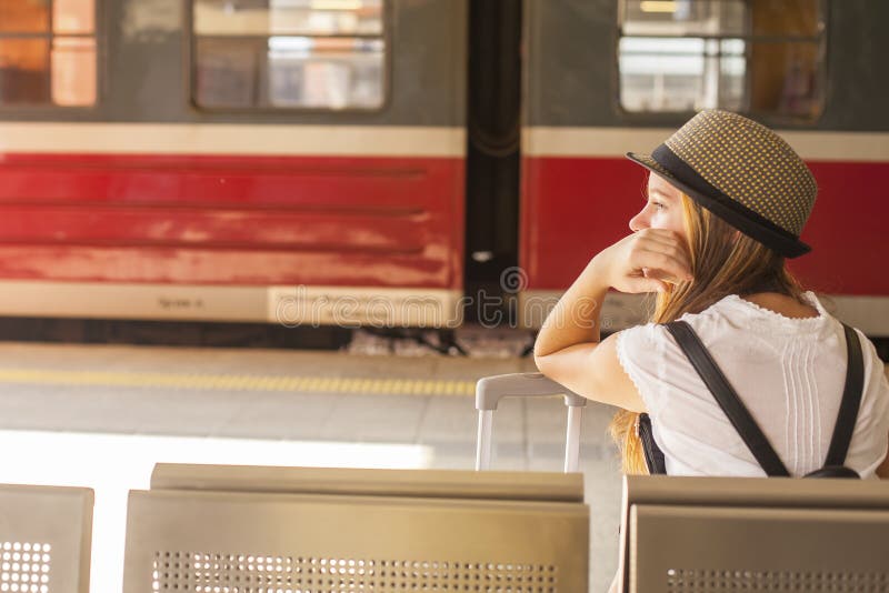 Young cute girl waiting for the train at the railway station.