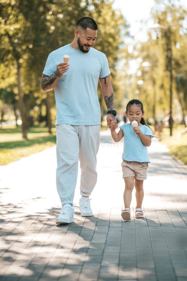 Young Dad and His Daughter Eating Icecream and Looking Enjoyed Stock