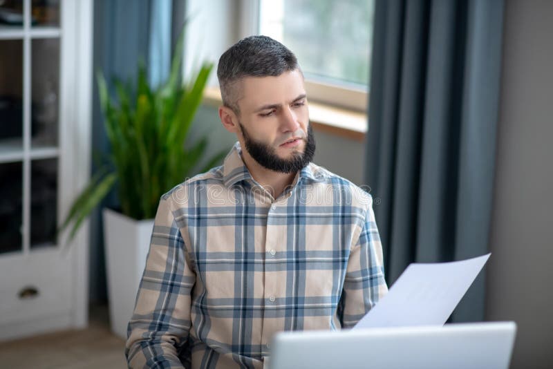 Young dark-haired bearded man in front of a laptop.