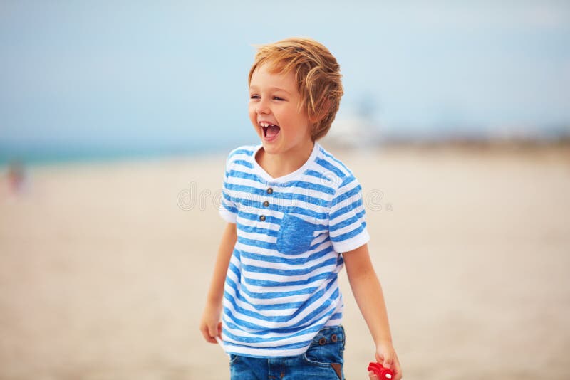 Young delighted boy, kid playing with a toy propeller, having fun on summer beach