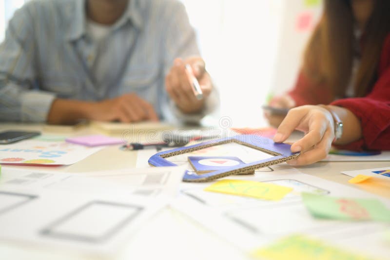 Young designer arranging sticky notes and app prototypes during a user experience UX design session royalty free stock photos