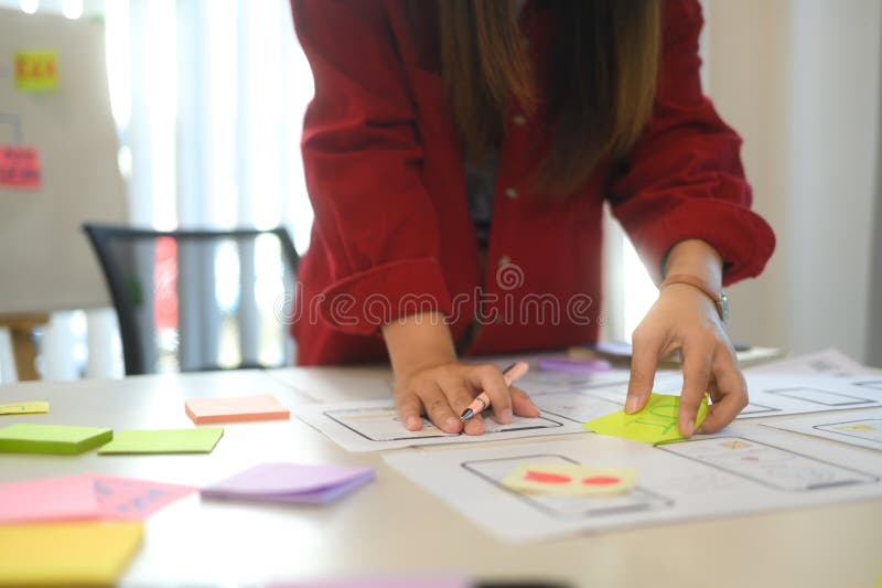 Young designer arranging sticky notes and app prototypes during a user experience UX design session stock photos
