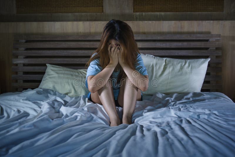 Young desperate and depressed woman crying in bed at night having depressio...