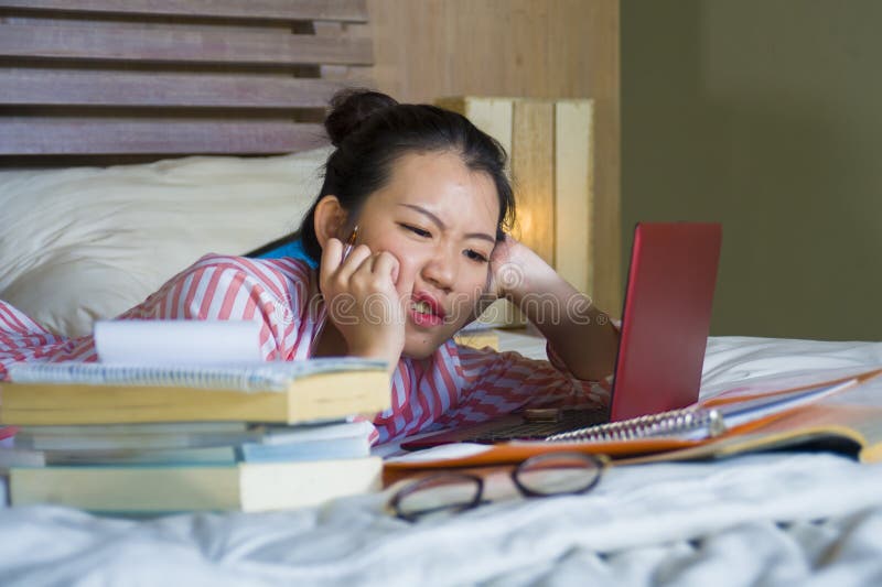 Young desperate and tired Asian Chinese university student girl feeling overwhelmed and stressed preparing exam studying with