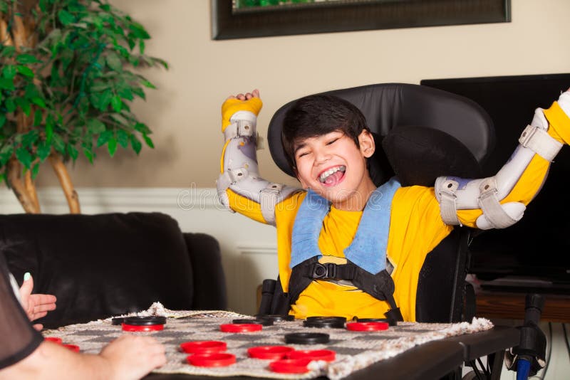 Young disabled boy in wheelchair playing checkers