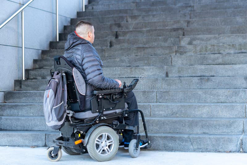 Young disabled man in a electric wheelchair in front of stairs royalty free stock photography Young disabled man in a electric wheelchair in front of stairs royalty free stock photography