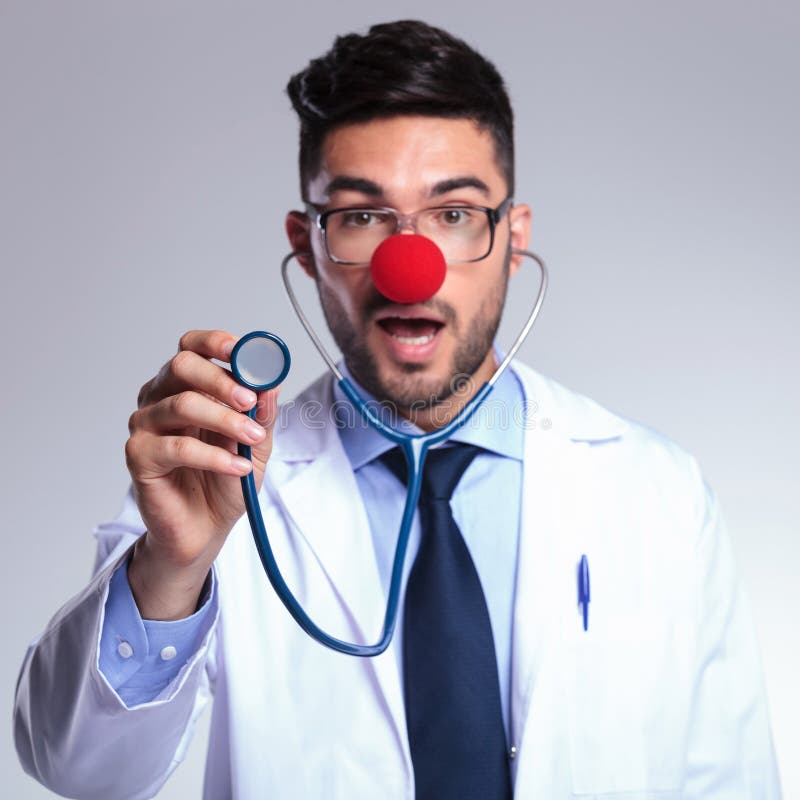 Young doctor listens to you at stethoscope with red nose stock images Young doctor listens to you at stethoscope with red nose stock images