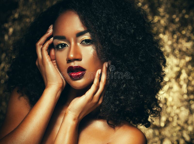 Young elegant african american woman with afro hair. Glamour makeup. Golden Background.