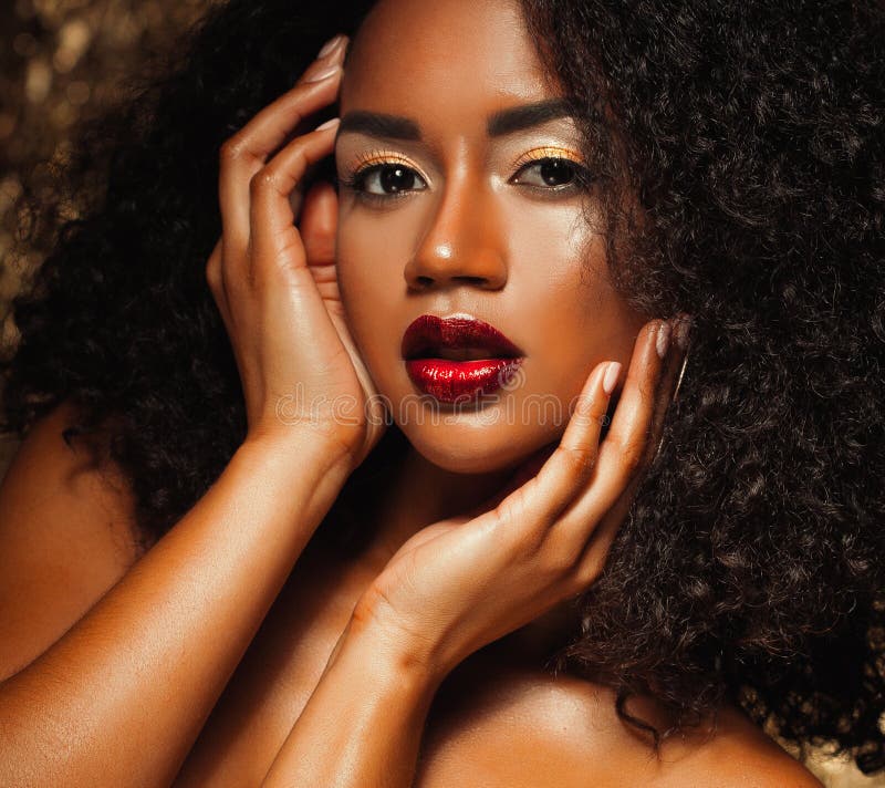 Young elegant african american woman with afro hair. Glamour makeup. Golden Background.