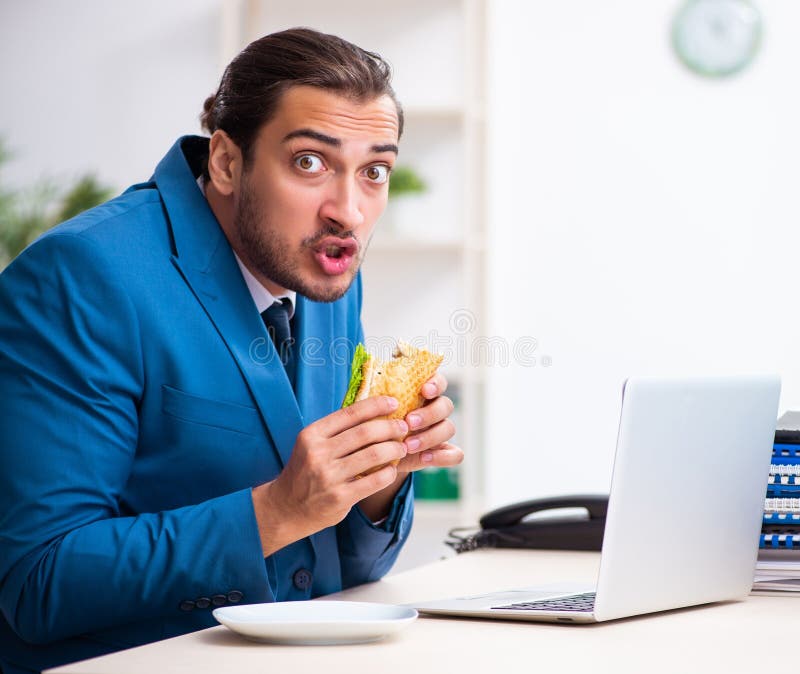 Young male employee having breakfast at workplace stock photography