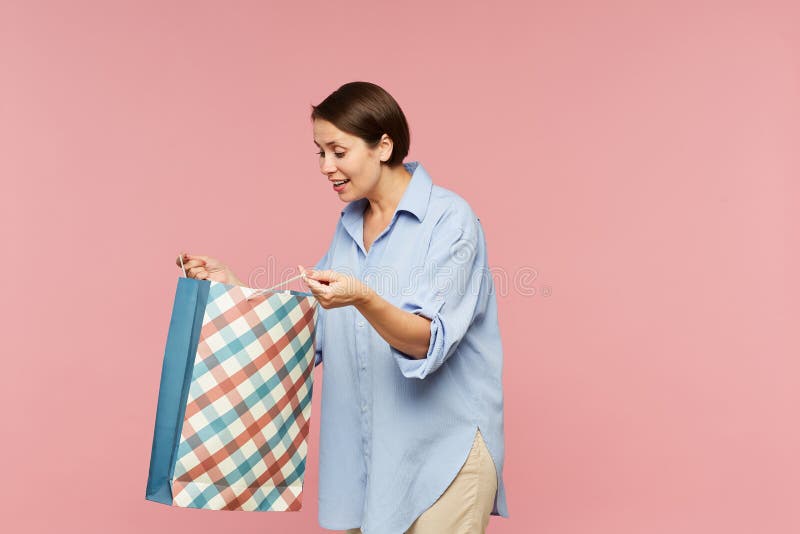 Young excited female in casualwear looking at surprise in open paperbag stock photography Young excited female in casualwear looking at surprise in open paperbag stock photography