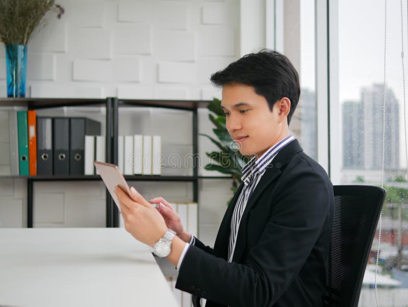 Young executive Asian man sit and smile on the chair and holding stock photography Young executive Asian man sit and smile on the chair and holding stock photography