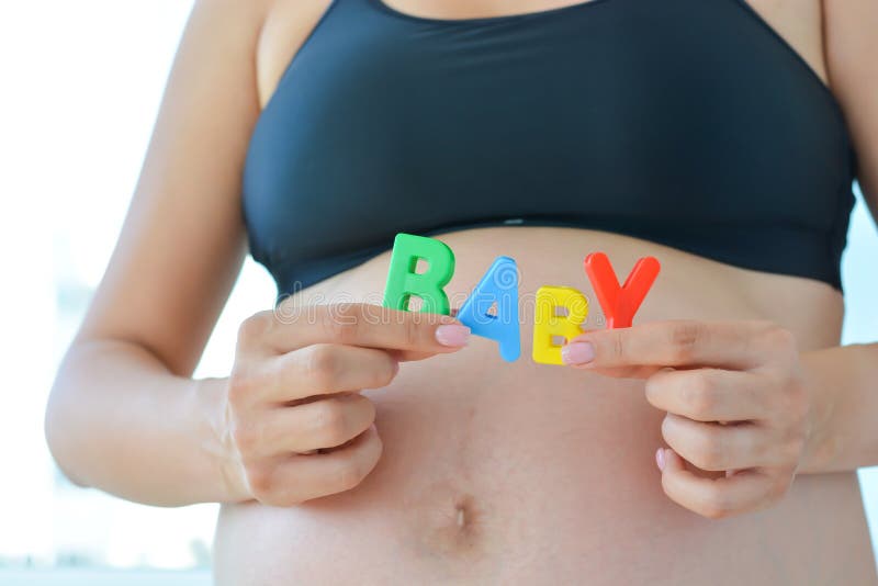 Young expectant mother with letter blocks spelling baby on her pregnant belly stock photos Young expectant mother with letter blocks spelling baby on her pregnant belly stock photos