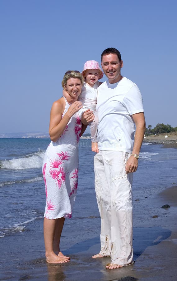 Giovane famiglia in piedi su una spiaggia assolata, in vacanza in Spagna, sulla Costa del Sol.