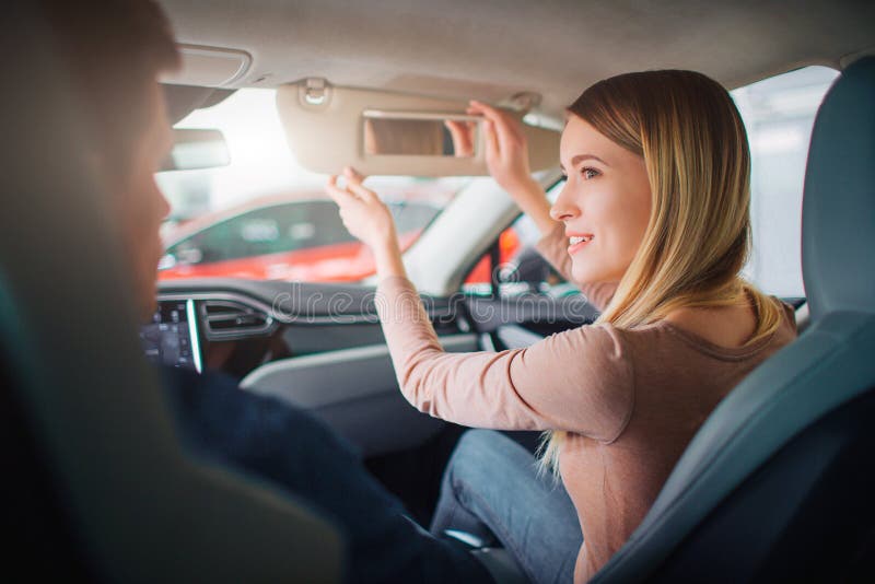 Young family buying first electric car in the showroom. Attractive smiling couple talking in the cabin of modern royalty free stock photo Young family buying first electric car in the showroom. Attractive smiling couple talking in the cabin of modern royalty free stock photo