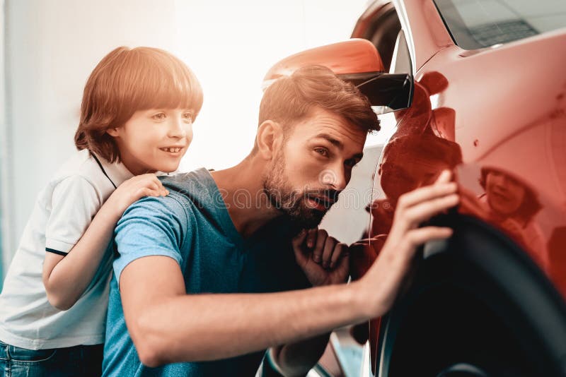 Young Family Are Choosing A New Car In Showroom. Automobile Salon. Father And Son. Good Mood. Make A Desicion. Auto Rewiew. Quality Control. Reliability Mark.