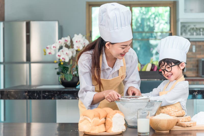 Young family cooking food in kitchen. Happy young girl with her mother mixing batter in the bowl royalty free stock photography Young family cooking food in kitchen. Happy young girl with her mother mixing batter in the bowl royalty free stock photography