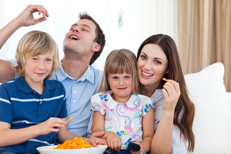Young family eating crisps while watching TV stock photography Young family eating crisps while watching TV stock photography
