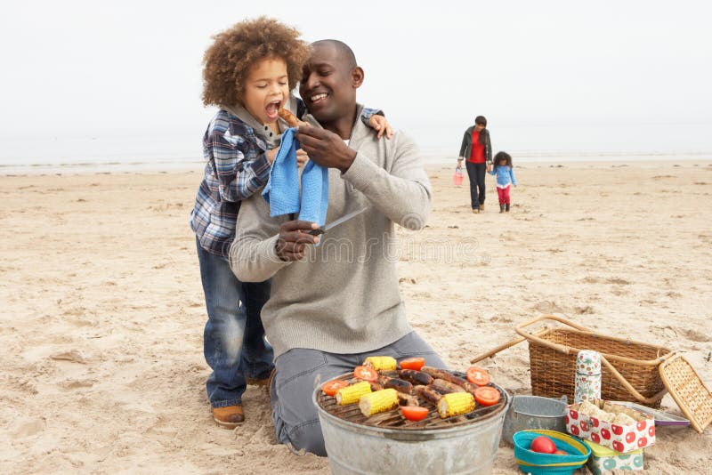 Young Family Enjoying Barbeque On Beach stock photography Young Family Enjoying Barbeque On Beach stock photography