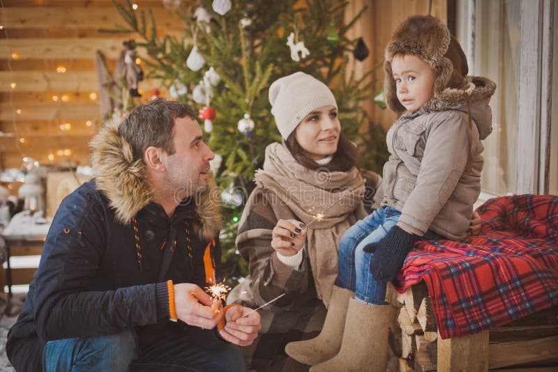 Young family enjoying their holiday time together, decorating Christmas tree outdoors in warm clothes royalty free stock photo Young family enjoying their holiday time together, decorating Christmas tree outdoors in warm clothes royalty free stock photo