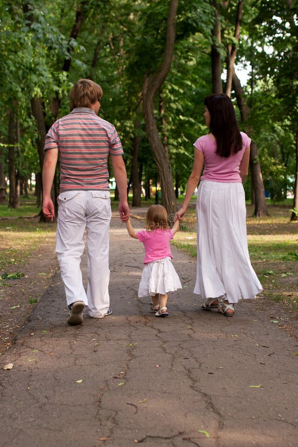 A young family, father, mother and toddler daughter walking in t