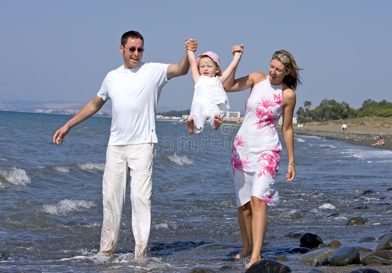 I giovani, la famiglia felice a piedi e a giocare con la figlia in mare, sulla spiaggia, in Spagna, durante la vostra vacanza.