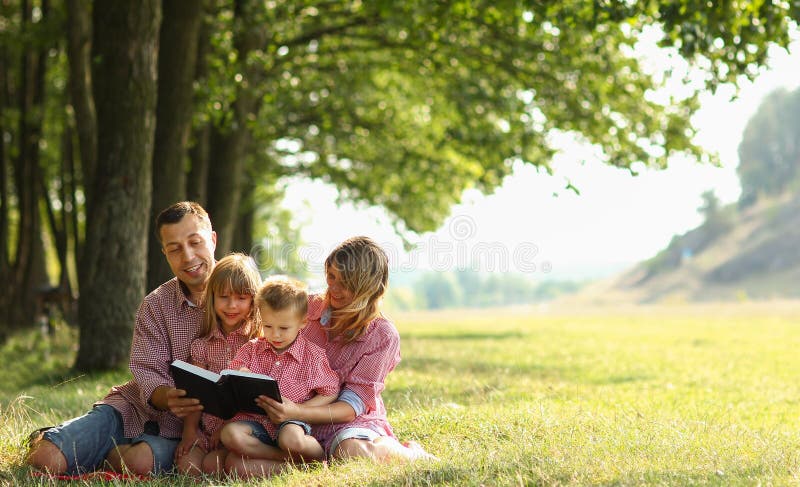 Young family reading the Bible in nature