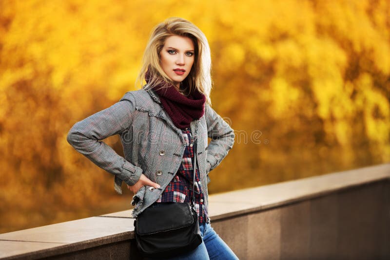 Young fashion blond woman in autumn city park