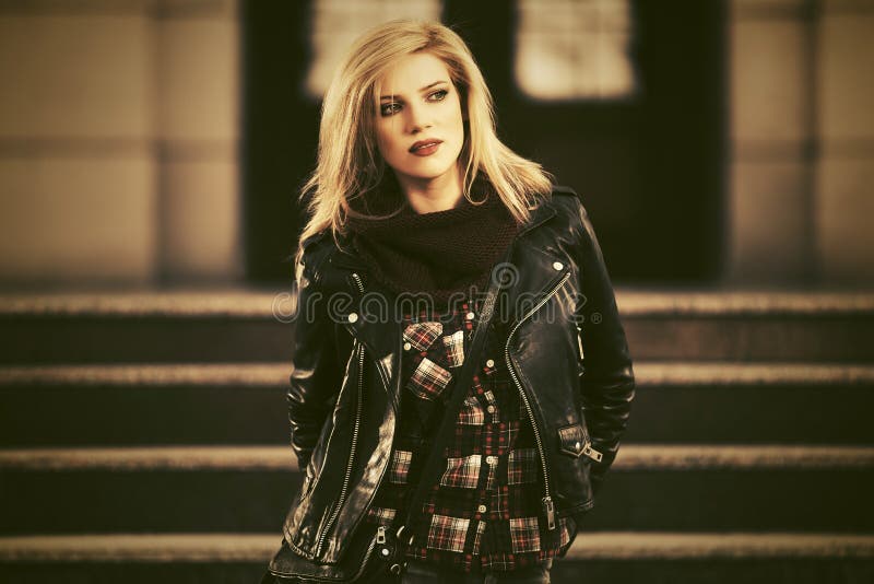 Young fashion blonde woman in leather jacket on city street