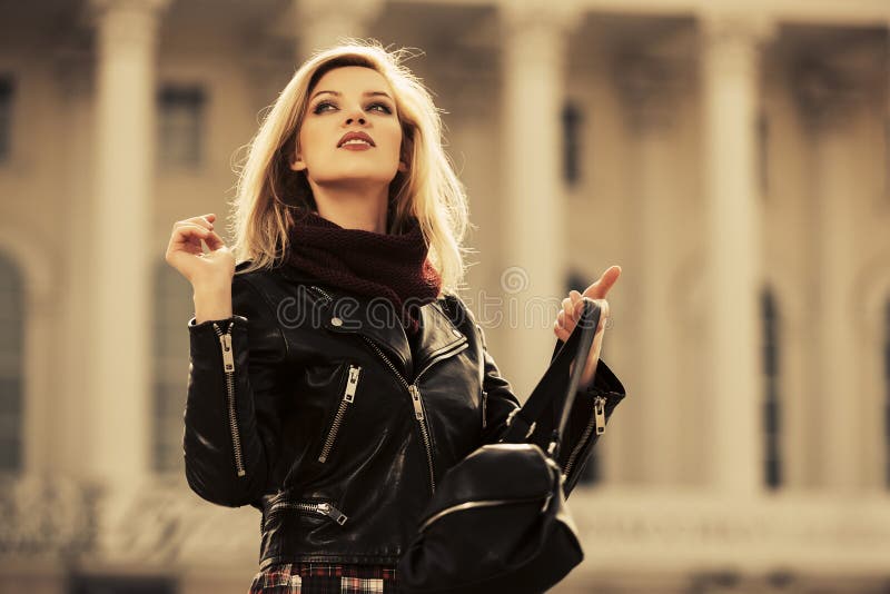 Young fashion blonde woman wearing leather jacket on city street