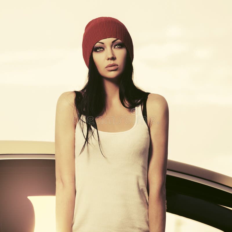 Young fashion hipster woman in white tank top standing beside her car royalty free stock photography Young fashion hipster woman in white tank top standing beside her car royalty free stock photography
