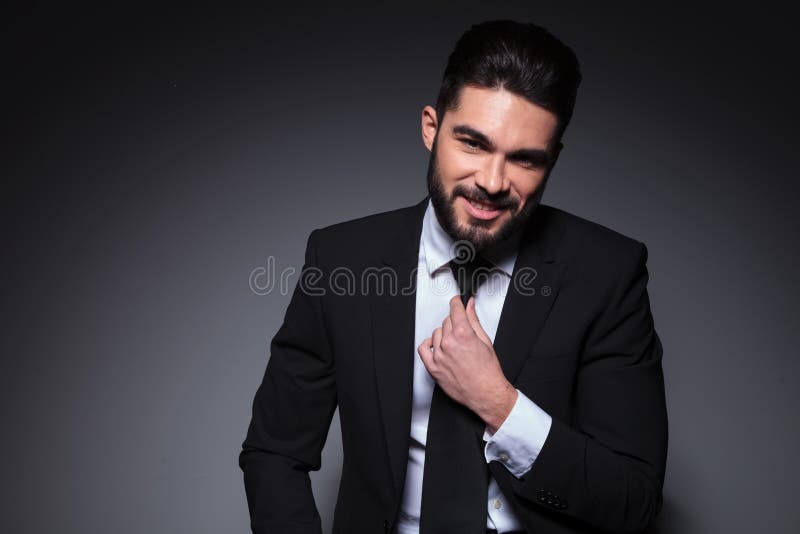 Young fashion man smiles and adjusts tie royalty free stock photography