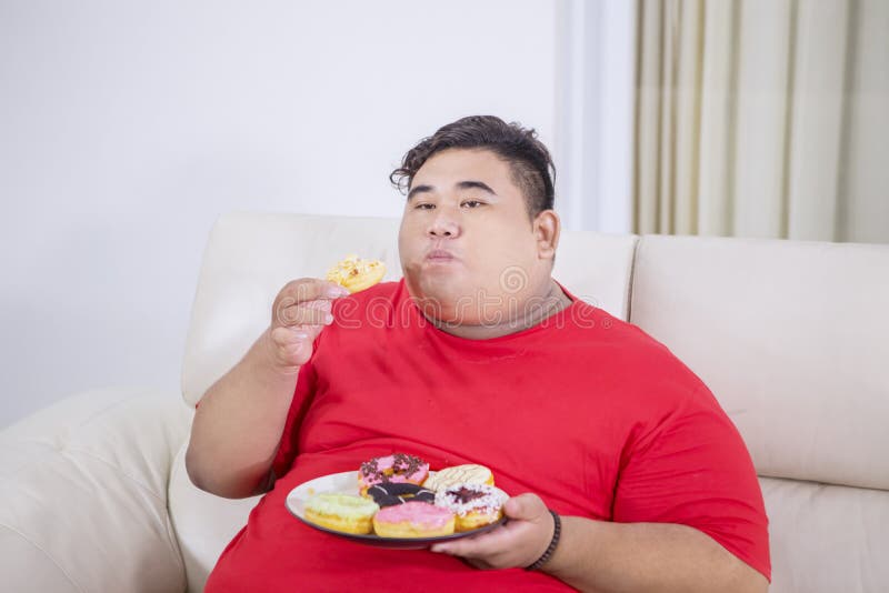 Fat Man Enjoying a Plate of Donuts on the Couch Stock Photo 