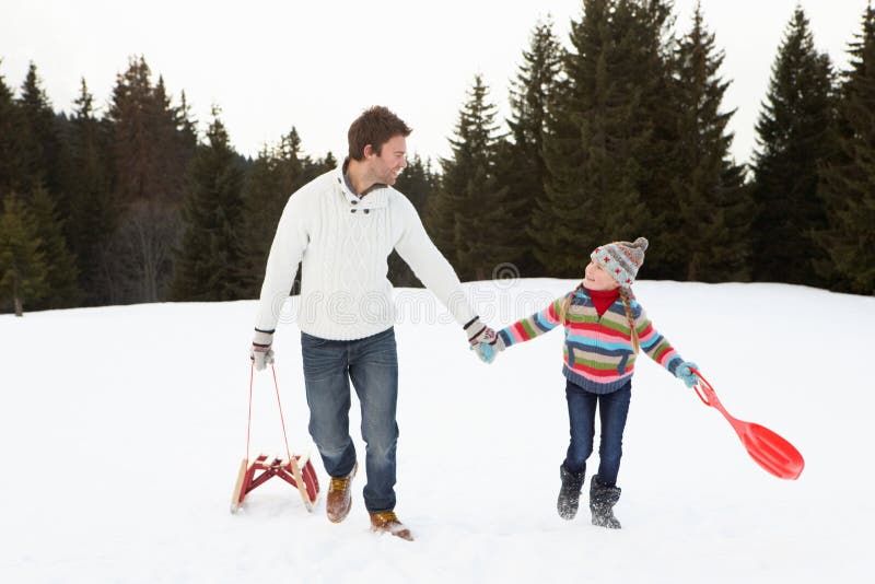 Young Father And Daughter Walking In Snow With Sle