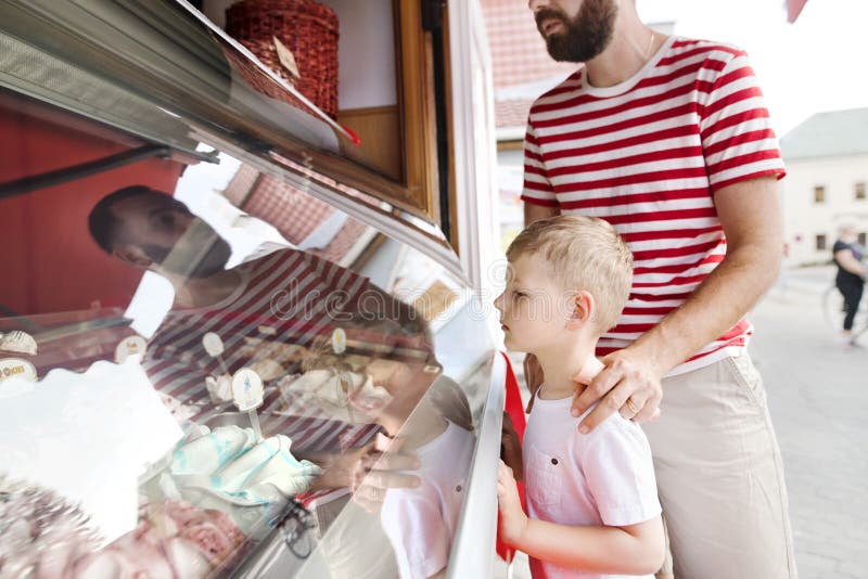 Young father and his little son buying ice cream. Sunny day.