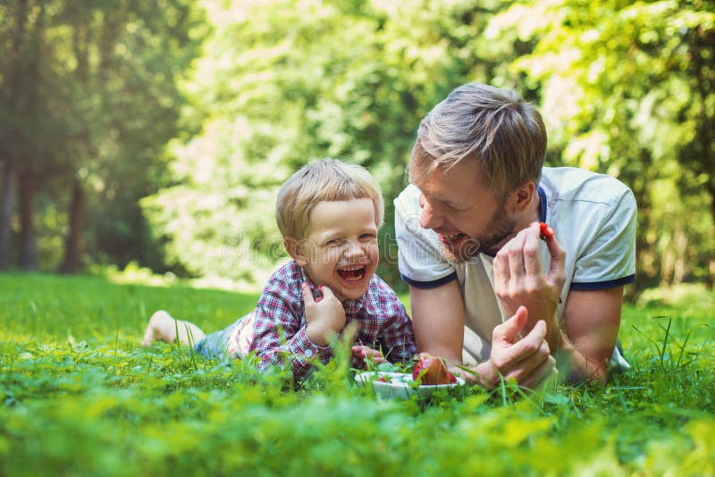 Young father and his son eating strawberries in Park. Picnic. Outdoor portrait