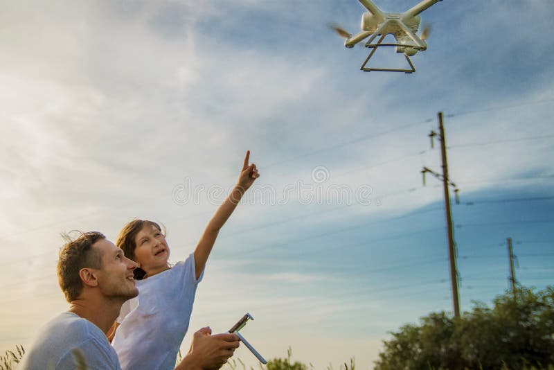 Young father shows his cute daughter how to control drone outdoors. royalty free stock photos Young father shows his cute daughter how to control drone outdoors. royalty free stock photos
