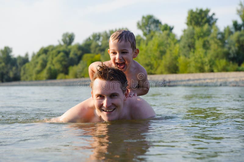 Young father and son swimming in river